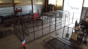 Cage en treillis métallique en construction dans un atelier industriel.