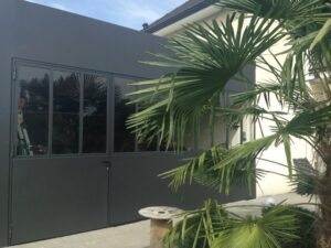 Verrière anthracite style atelier sur extension moderne avec palmier.